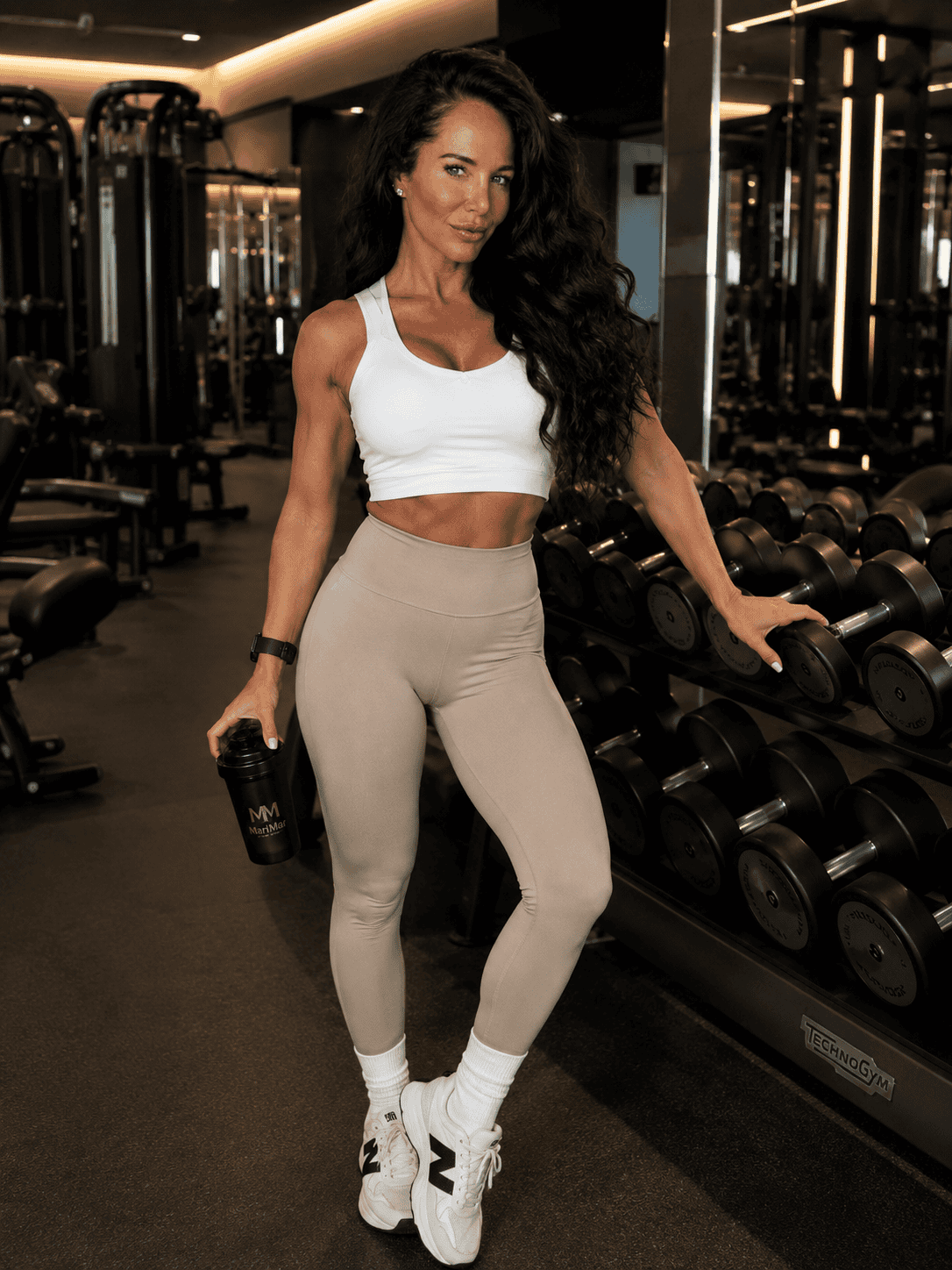 Fit woman in workout gear lifting dumbbell in gym.