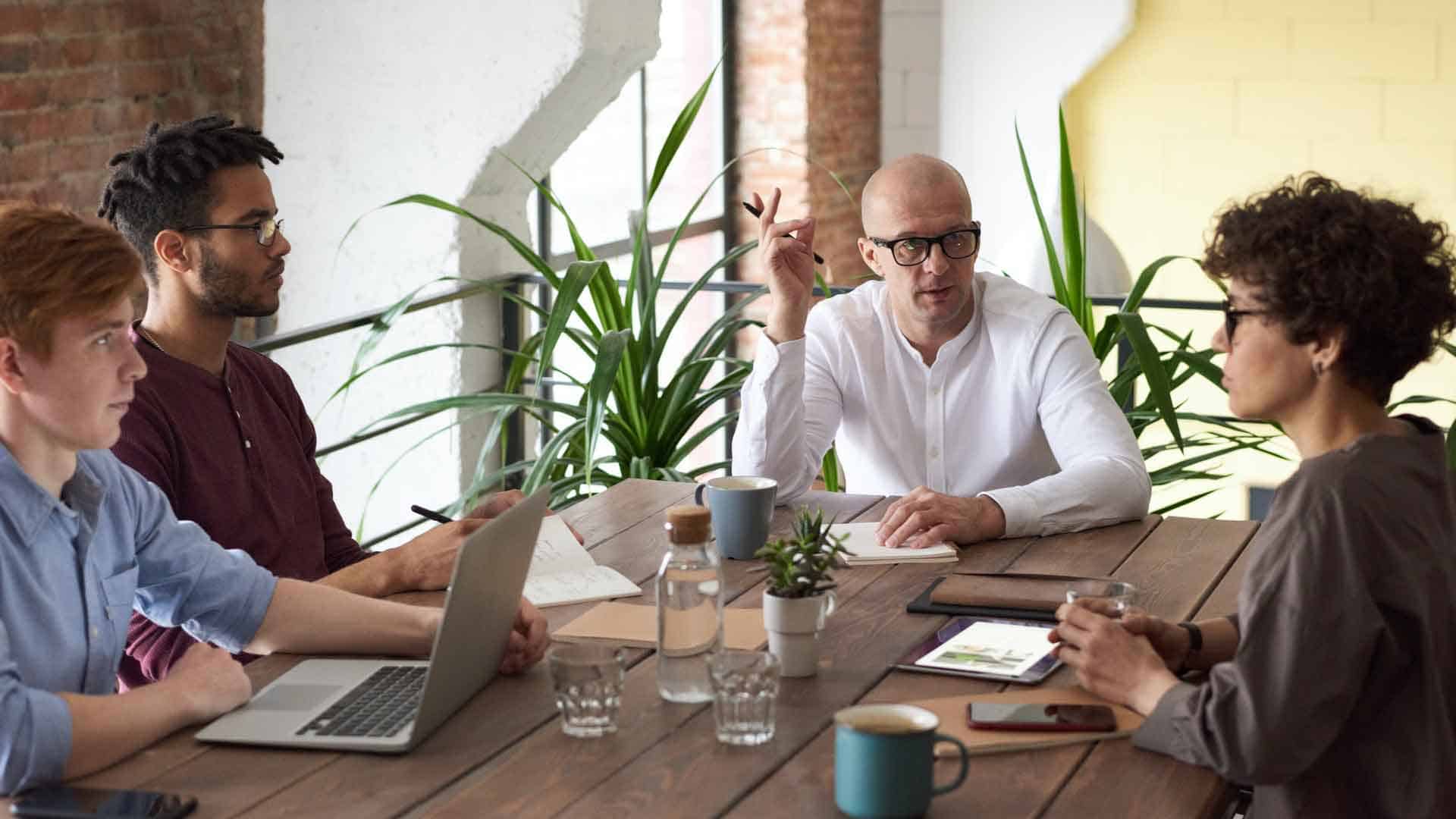 Business meeting with diverse team discussing strategies at a wooden table.