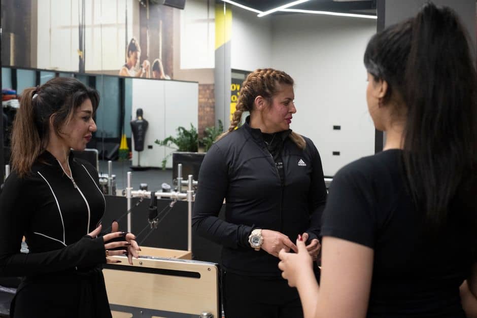Three women engaging in a fitness discussion at the gym.